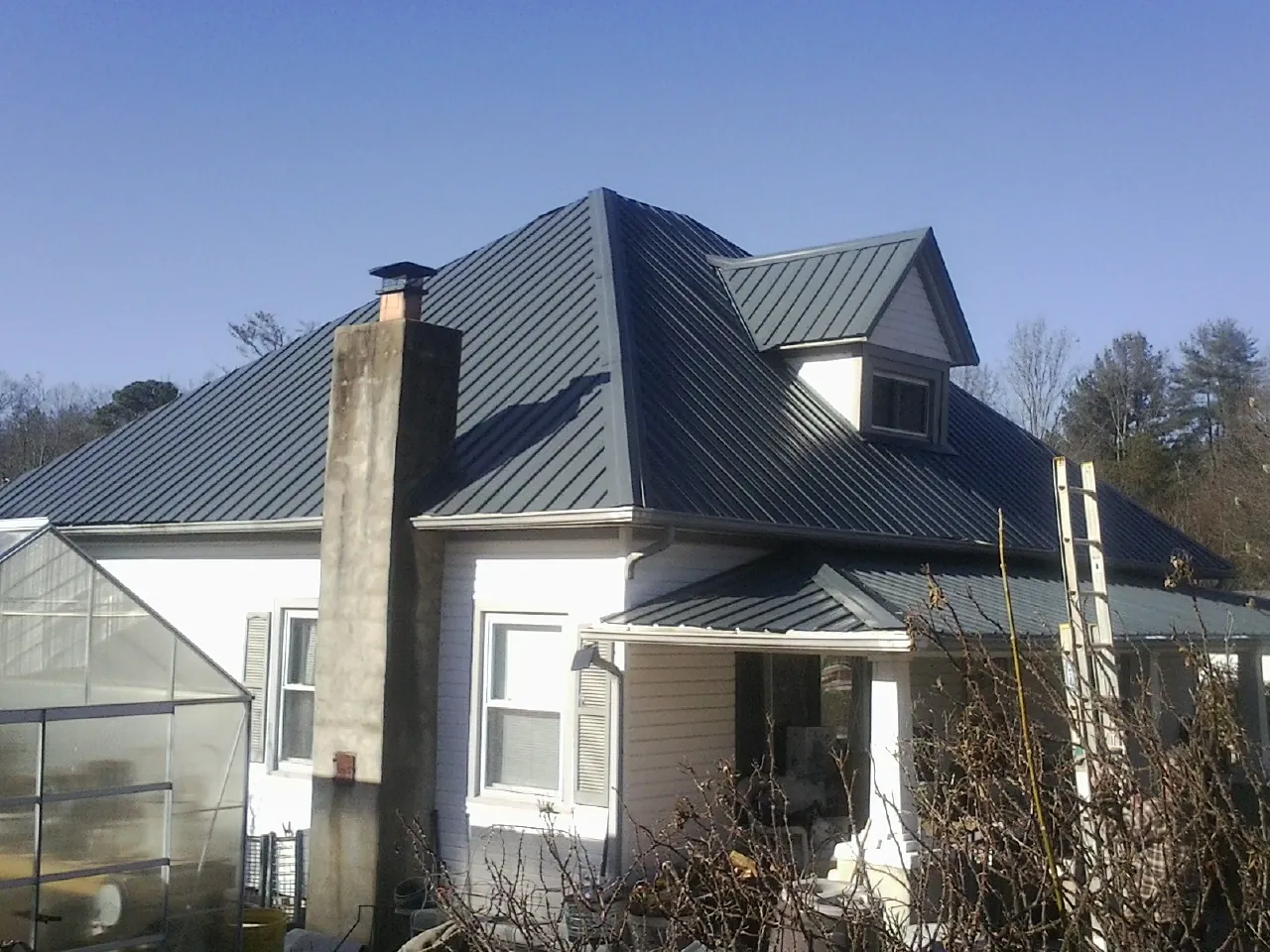 Dark blue standing seam metal roof on a white farmhouse with dormer — Slate & Tile Roof Repair by Roofing Brothers in Yates City