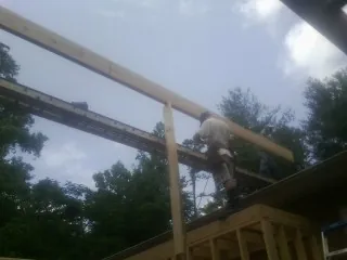 Carpenter setting a ridge beam over a new addition frame — Ice Dam Removal by Roofing Brothers in Yates City
