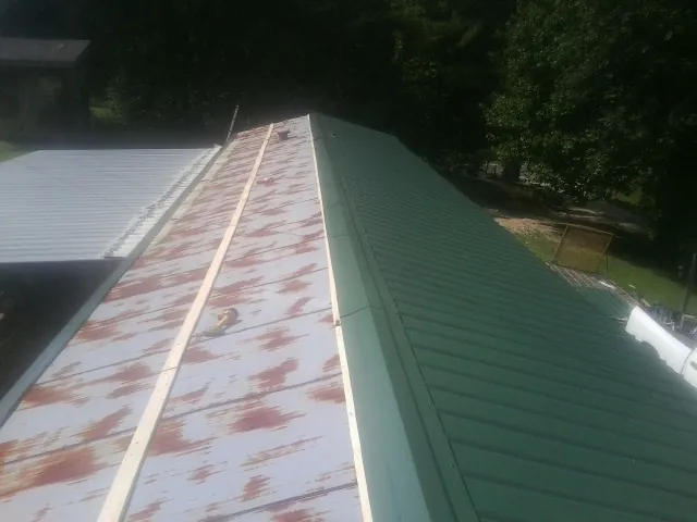 Old rusted panels beside newly installed green metal roofing — Wind Damage Roof Repair by Roofing Brothers in Yates City