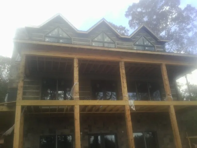 Dormers and porch framing on a large log home under construction — Roof Coating work by our crew in Yates City