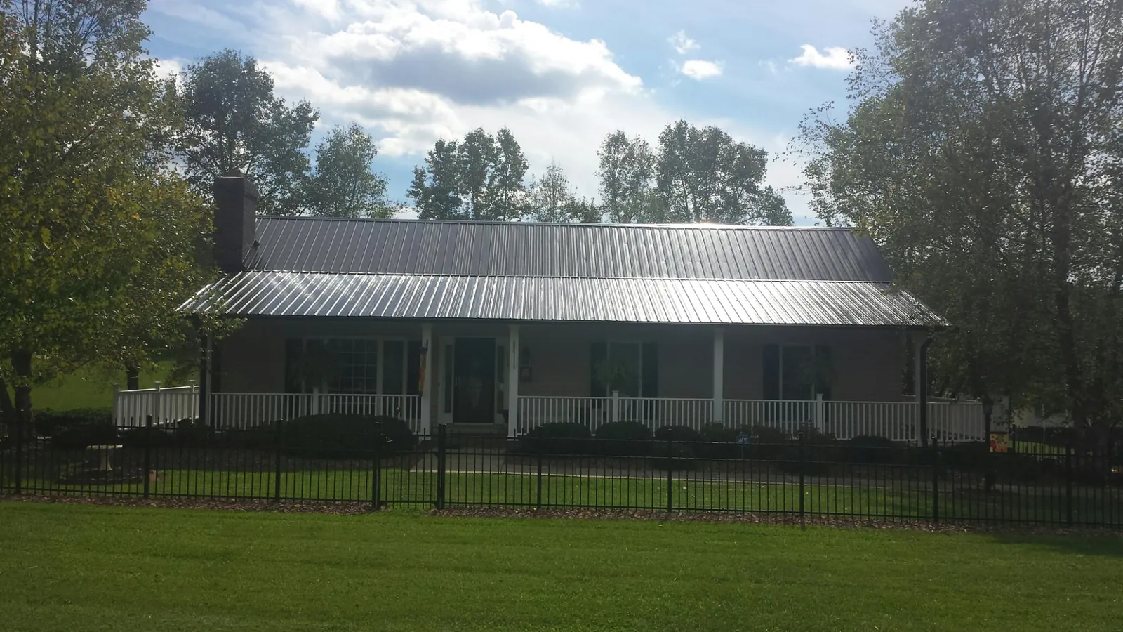 Gray metal roof on a brick ranch with a full width front porch — Gutter Guard Installation work by our crew in Yates City