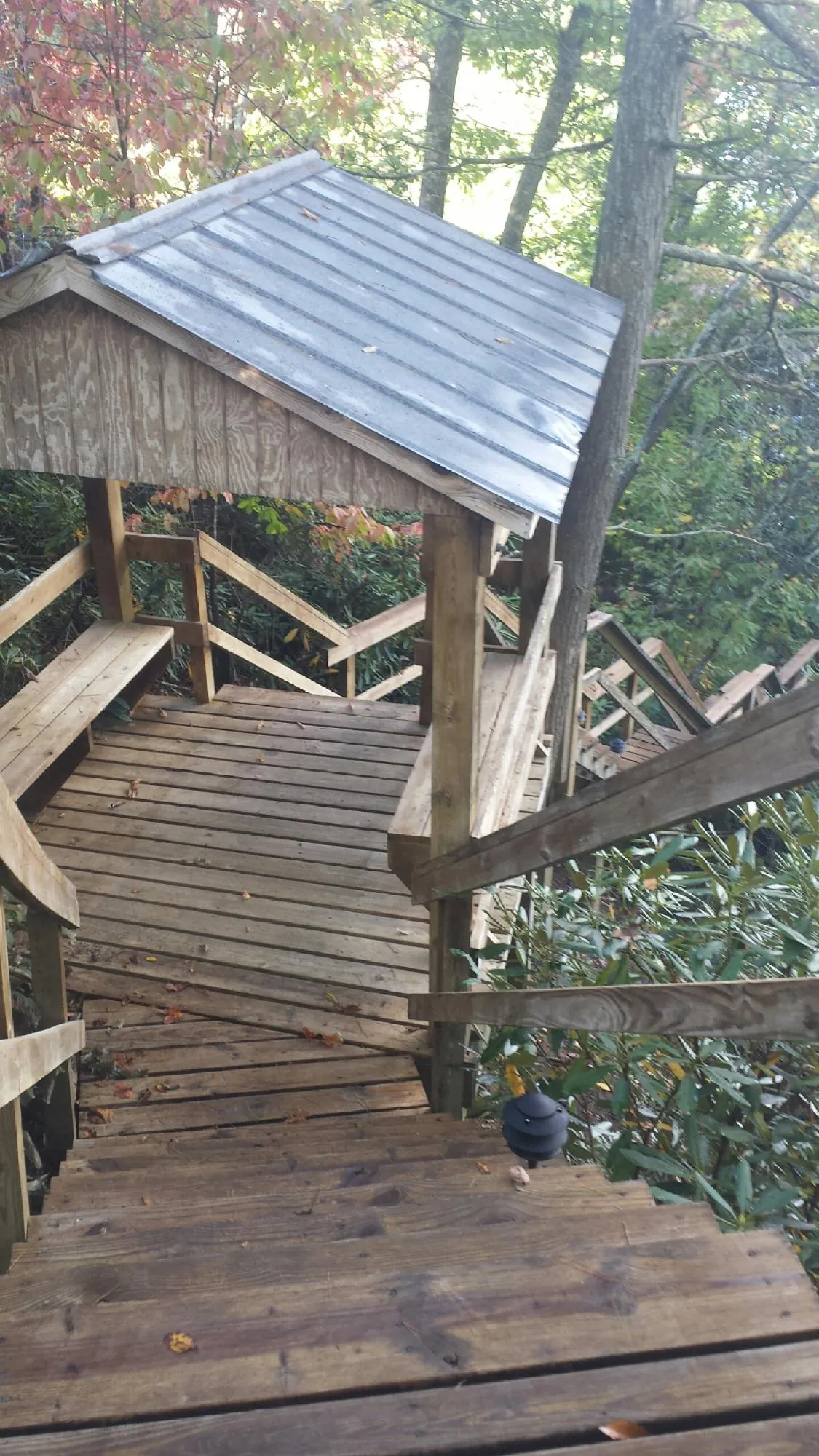 Metal roofed shelter over wooden steps on a wooded walkway — Skylight Repair & Installation work by our crew in Yates City