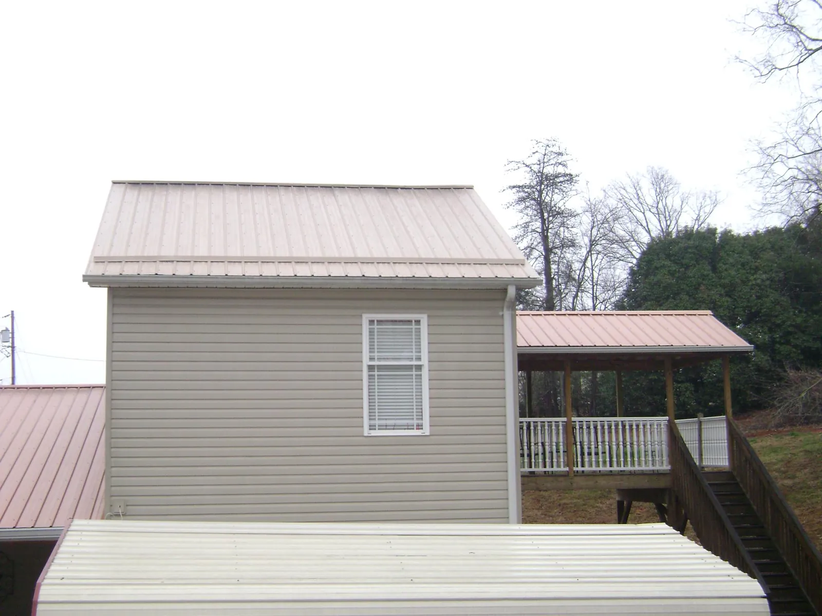 Tan metal roofs on a two story addition and attached porch, from a Roof Replacement job in Yates City