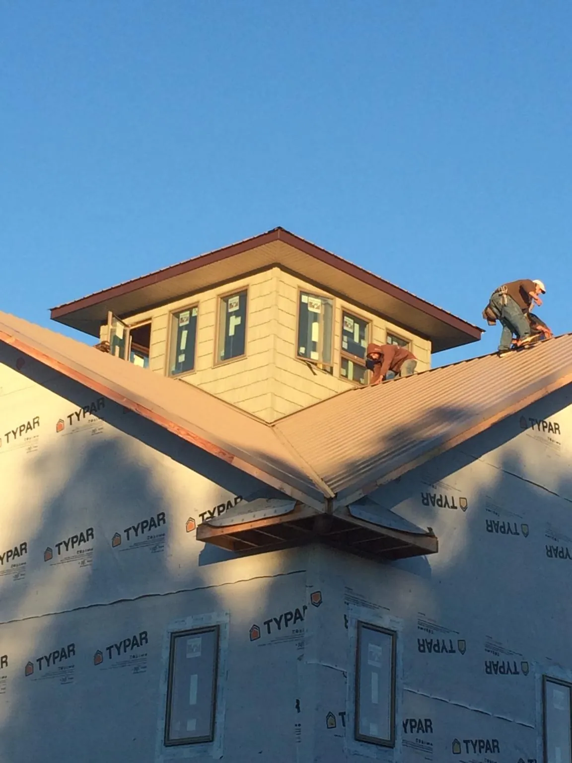 Roofers working around a rooftop cupola on a new metal roof at sunset — Roof Waterproofing in Yates City by Roofing Brothers